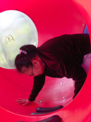 6 photos show Nanta inside colorful round tubes, crawling on her hands and knees.  When she reaches the tubular slide, she turns around and puts her feet into the slide and goes down, laughing.